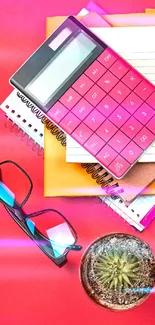 Colorful desk items with pink calculator and cactus.