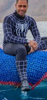 Diver in black wetsuit on a blue raft in scenic waters.