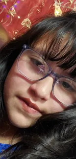 Girl with glasses against a rich red background.