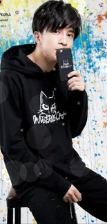 Young man in black hoodie with graffiti background wallpaper.