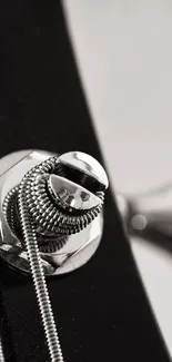 Close-up of a guitar with shining metal strings and black body.