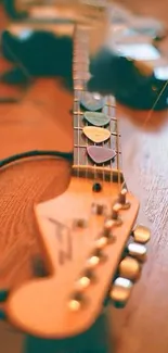 Artistic close-up of a vintage guitar headstock with picks on wooden floor.