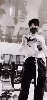 Monochrome gym scene with masked person preparing for workout.