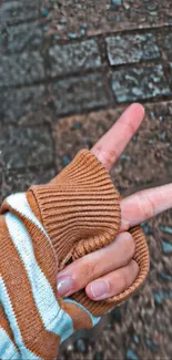 Hand gesture with striped sweater against textured background.