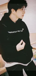 Fashionable person in black hoodie, cozy wallpaper aesthetic.