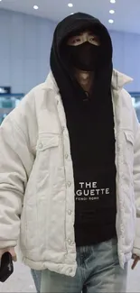 Stylish individual in white jacket with black hoodie at airport.