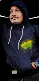 Person in black hoodie with vibrant yellow splash design on mobile wallpaper.