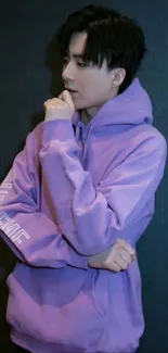 Person in purple hoodie posing against a dark background.