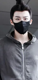 Person wearing grey hoodie and black mask, stylish and modern.