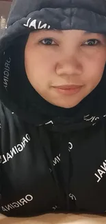 Person wearing a black hoodie with white text print.