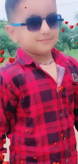 Child in red checkered shirt with sunglasses outdoors.