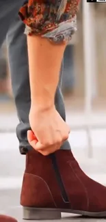 Close-up of a stylish brown leather boot being worn outdoors.