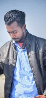 Person wearing leather jacket with blue sky backdrop.