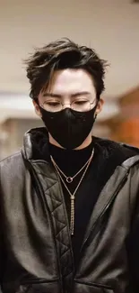 Person in black leather jacket with mask and glasses, stylish urban portrait.