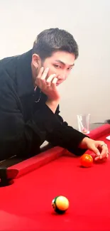 Man thoughtfully leaning over a red pool table with billiard balls.