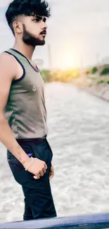 Stylish man standing by the riverside at sunset.