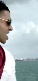 Man wearing sunglasses standing by the ocean.