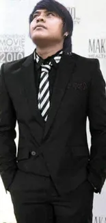 Man in a formal black suit with a striped tie, glancing upwards.