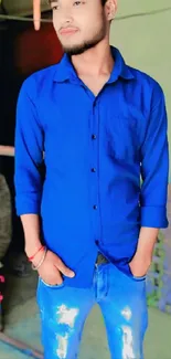 Man standing in blue shirt and jeans.