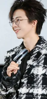 Man in checkered jacket holding a microphone, smiling.