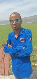 Man in blue shirt stands in vibrant green field.