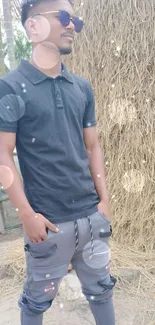 Man in black shirt standing outdoors with hay background.