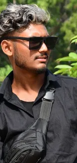 Man in sunglasses, black shirt with nature background.