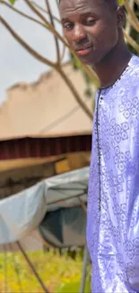 Man posing in stylish purple patterned outfit outdoors.