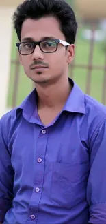 Man wearing a stylish purple shirt and glasses in an outdoor setting.