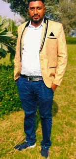 Man in tan jacket standing in a vibrant green garden.