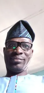 Man wearing stylish traditional attire with blue hues and glasses.