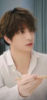 Stylish man in white shirt sitting indoors.