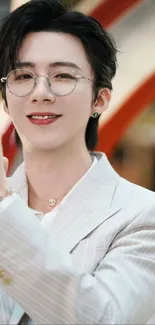 Man in a white suit with glasses and a friendly smile.