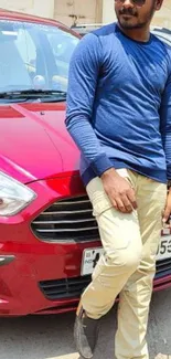 Man leaning on a red car wearing a stylish outfit.