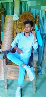 Man sitting on a wooden throne chair in a colorful room setting.