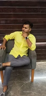 Stylish man posing against a wooden panel background in casual attire.