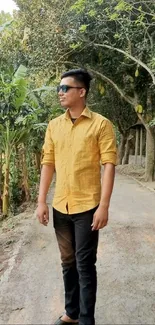 Man in yellow shirt walking on tree-lined path.