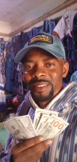 Man in stylish attire holding dollar bills in a colorful clothing store.