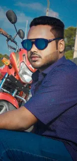 Man in sunglasses leaning against a red motorcycle.