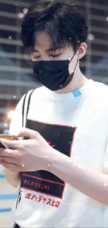 Stylish young man wearing a mask, using a smartphone in a modern setting.