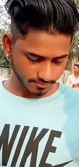 Young man in light blue shirt using smartphone outdoors.