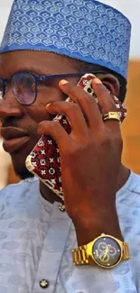 Man in traditional blue attire with stylish phone and watch.