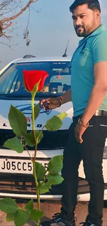 Stylish man in teal shirt with red rose near white car.