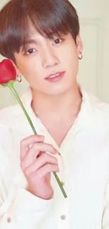 Man holding a single red rose in an elegant pose.