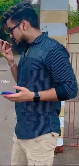 Man in navy shirt using smartphone outdoors.