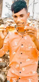 Trendy young man with sunglasses and orange shirt outdoors.