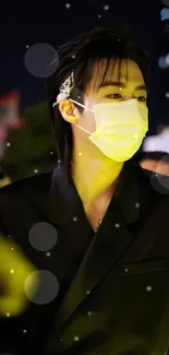 Fashionable night portrait with mask and black outfit glowing under urban lights.