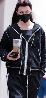 Person in black attire holding a coffee.