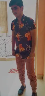 Young man in floral shirt with peach pants in stylish pose.