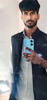 Man takes a stylish mirror selfie with blue phone.